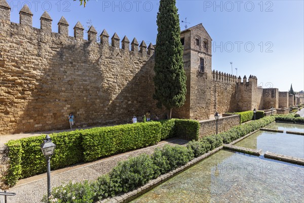 Historic city wall with adjoining green area and water surface under a blue sky, Cordoba