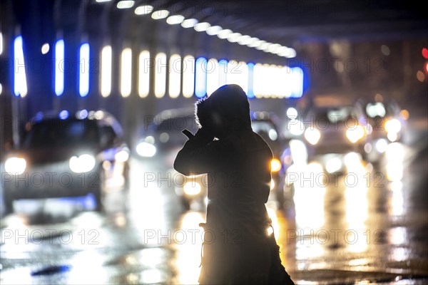 Illuminated subway at the main railway station, pedestrians at a pedestrian crossing, rainy weather, city centre, in the evening, Essen, North Rhine-Westphalia, Germany, Europe