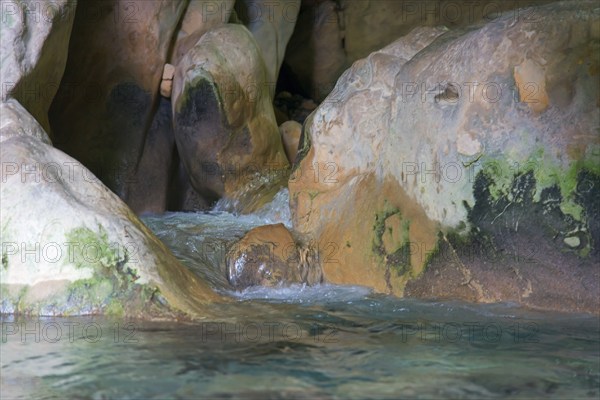 Water flows through a rocky cave with moss-covered stones, a peaceful and natural environment, Gruta Rio Cuadros, near Bedmar y Garcíez, Bedmar y Garciez, Sierra Mágina Natural Park, Jaén province, Jaen, Andalusia, Spain, Europe