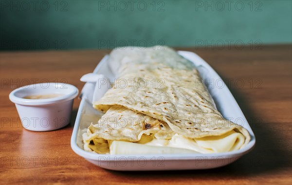 Close up of a Nicaraguan quesillo served on wooden table. Top view of Nicaraguan Quesillo on a plate served on wooden table. Delicious traditional Nicaraguan quesillo served on wooden table