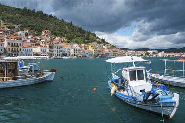 Harbour town with boats in the foreground and a forested range of hills in the background under a cloudy sky, Harbour, Gythio, Mani, Laconia, Peloponnese, Greece, Githio, Gythion, Europe