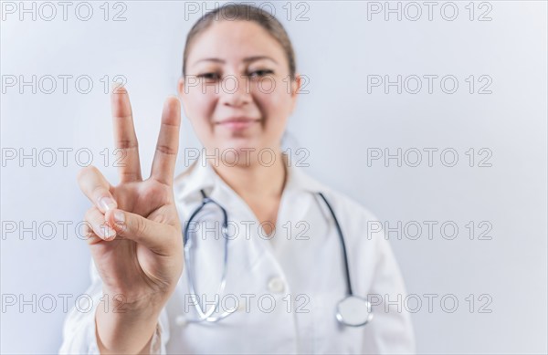 Female doctor counting number TWO isolated. Young female doctor counting number 2 on isolated background