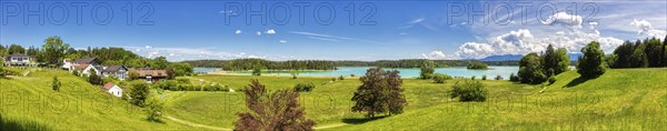 A panorama of a village on a lake with surrounding meadows and mountains, Osterseen