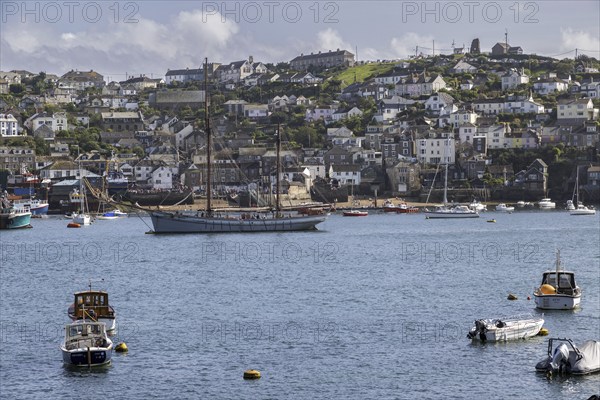 Sailing ship and boats on the water with a coastal town in the background, Fowey Landing, Cornwall, England, Great Britain