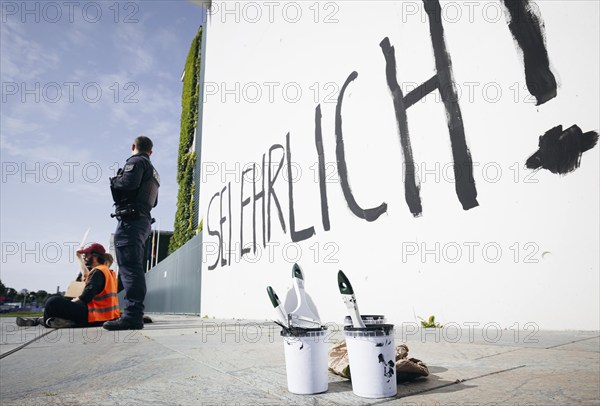 Demonstrators sit with signs in front of the Federal Chancellery, the demonstrators have written SEI ERHRLICH ! on the facade of the Federal Chancellery with black paint in Berlin, 06.06.2024