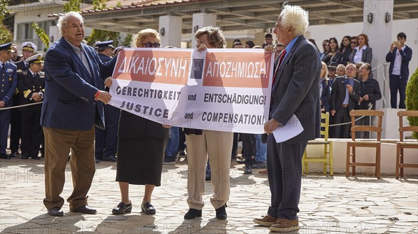 People holding banners with demands for justice and compensation, visit of Federal President Frank-Walter Steinmeier to Kandanos on 31 October 2024, Federal President, Frank-Walter Steinmeier, memorial, war crimes, Nazis, Wehrmacht crimes, World War II, Kandanos, southwest Crete, Crete, Greek islands, Greece, Europe