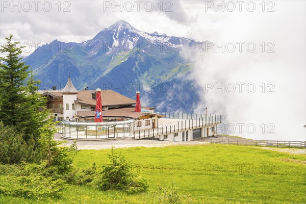 A building on a hill in front of a mountain backdrop with clouds and a green meadow, quiet and idyllic, Penken, Zillertal, Austria, Europe
