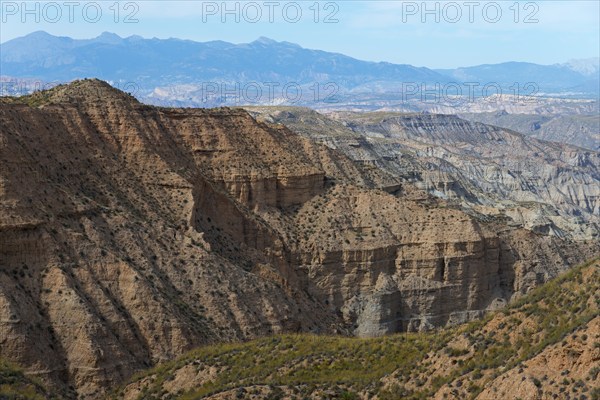 Hilly and dry desert landscape with mountains in the background under a blue sky, Gorafe desert, Granada, Andalusia, Spain, Europe