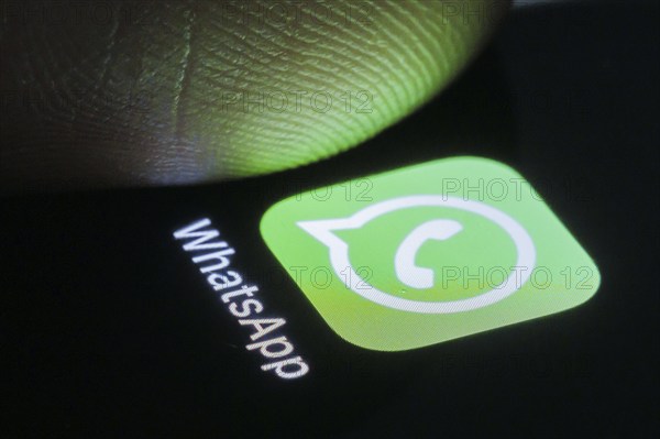 The WhatsApp app can be seen on your smartphone next to a finger. Berlin, 27.03.2024