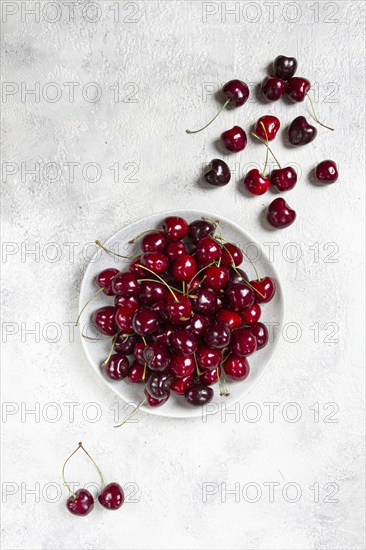 Red cherry, cherry berry, scattered on a plate, top view, no people