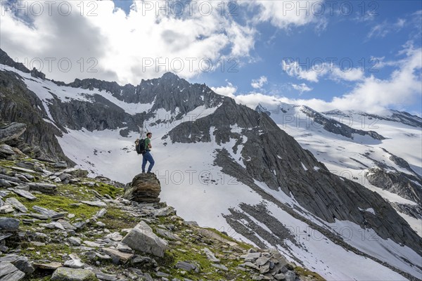 Mountaineer on a rock, rocky mountain peak Furtschaglspitze in the background, glaciated peak Großer Möseler with Furtschaglkees, ascent to Schönbichler Horn, Berliner Höhenweg, Zillertal Alps, Tyrol, Austria, Europe
