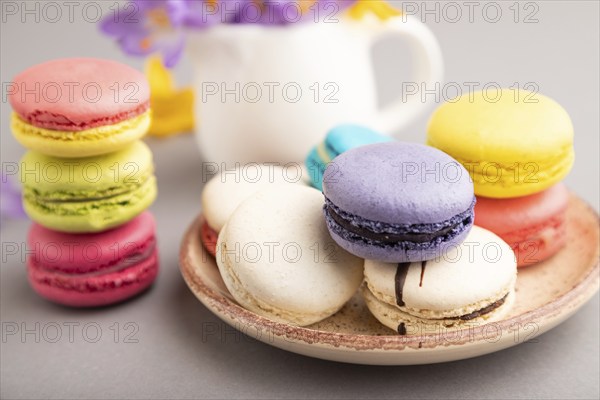 Multicolored macaroons with spring snowdrop crocus flowers on gray pastel background. side view, close up, still life, selective focus. Breakfast, morning, spring concept