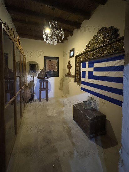 Chamber room with festive chandelier chandelier right Greek national flag flag of Greece in Xopatera Tower Tower of Xopateras from 19th century in Unesco Site Site Orthodox Greek Orthodox Monastery Moni Odigitria, Festos, Crete, Greece, Europe