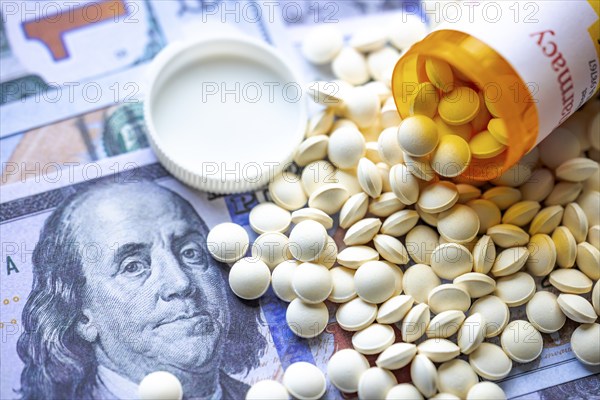 An open medicine pill container on American bills. Concept: American opioid crisis or American health care crisis