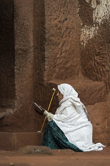 Ethiopian Orthodox woman prays at the entrance to the rock-hewn church of Biete Gabriel-Rufael, Lalibela, Ethiopia, Africa