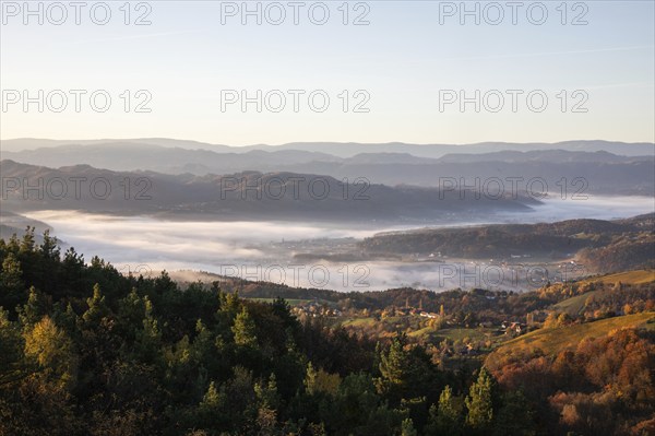 Autumn atmosphere in the morning light, fog drifts over forest with foliage colouring, vineyards and hilly landscape, view from the Demmerkogel lookout point, St. Andrä-Höch, Sausal wine country, Styria, Austria, Europe