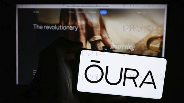 Stuttgart, Germany, 07-11-2024: Person holding mobile phone with logo of Finnish health technology company Oura Health Oy in front of business web page. Focus on phone display, Europe