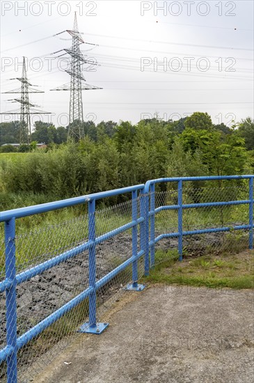 Blue metal railing in front of high voltage pylons