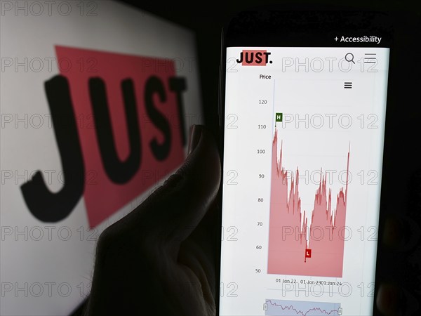 Stuttgart, Germany, 03-23-2024: Person holding cellphone with website of British financial services company Just Group plc in front of logo. Focus on center of phone display, Europe