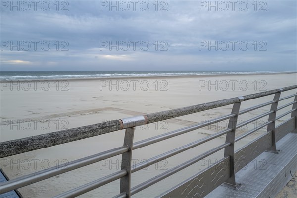 Metal railing in front of the empty beach and sea in the evening
