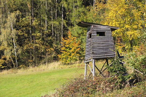 Wooden lookout tower for hunting in the woods and trees with colored leaves in autumn