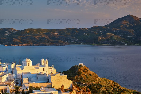 View of Plaka village on Milos island with traditional greek white houses with Greek Orthodox christian churck on sunset. Plaka town, Milos island, Greece, Europe