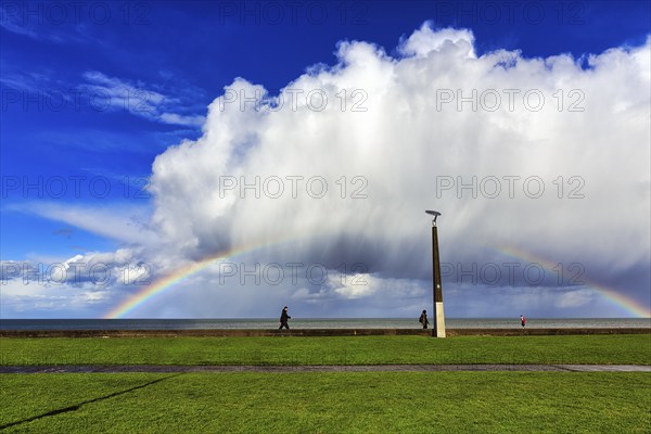 Pedestrians on seafront, dramatic cloudy sky with rainbow, Bray, Wicklow, Ireland, Europe
