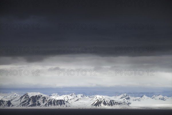 Black rain clouds over snow covered mountains along Isfjorden, second longest fjord at Spitsbergen, Svalbard