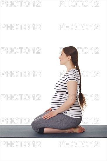 Pregnancy yoga exercise, pregnant woman doing yoga asana Virasana Hero Pose on knees isolated on white background