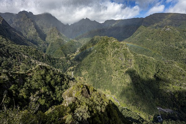 Densely overgrown steep mountains with rainbow, green mountain landscape, view from Miradouro dos Balcões, mountain valley Ribeira da Metade and the central mountains, Madeira, Portugal, Europe