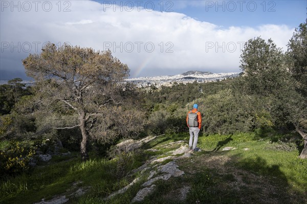 Tourist looking over the city with rainbow, Philopappos Hill, in the evening light, Athens, Attica, Greece, Europe