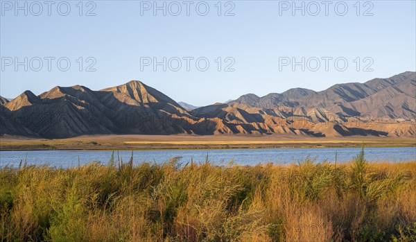 Blue Toktogul reservoir between dry mountain landscape, hilly mountains in the evening light, Jalalabad region, Kyrgyzstan, Asia