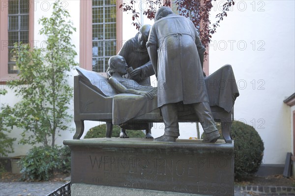 Sculpture and memorial to Werner Senger, three, figures, bed, lie, help, care, sick person, Wilhelmitenkloster, Old Town, Limburg, Hesse, Germany, Europe