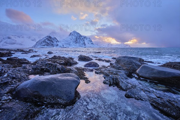Beach of Norwegian sea on rocky coast in fjord on sunset in winter. Vareid beach, Lofoten islands, Norway, Europe