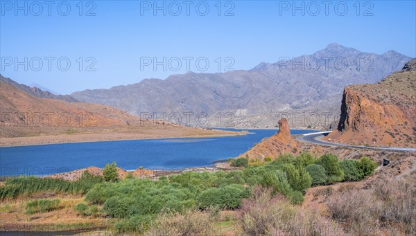 Blue Toktogul reservoir between dry mountain landscape with red mountains, Jalalabad region, Kyrgyzstan, Asia