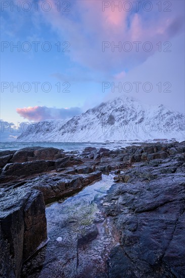 Beach of Norwegian sea on rocky coast in fjord on sunset in winter. Vareid beach, Lofoten islands, Norway, Europe