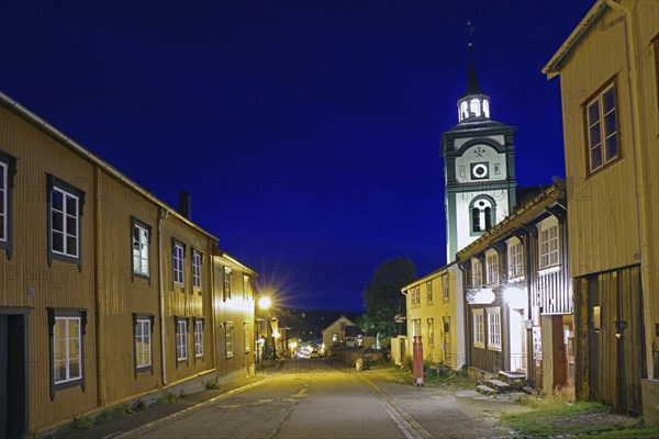 Street view of a traditional town at night with illuminated old buildings and a church tower, Miners' Church, Unesco World Heritage Site, Miners' Town, Röros, Norway, Europe