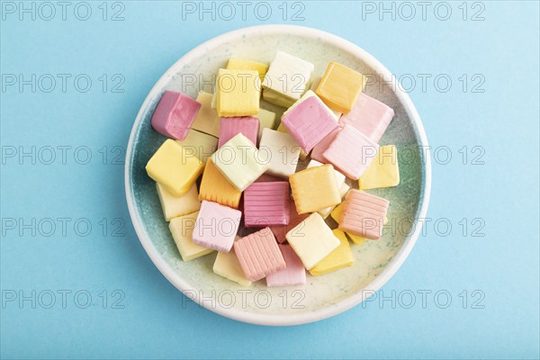 Various fruit jelly chewing candies on plate on blue pastel background. apple, banana, tangerine, top view, flat lay, close up