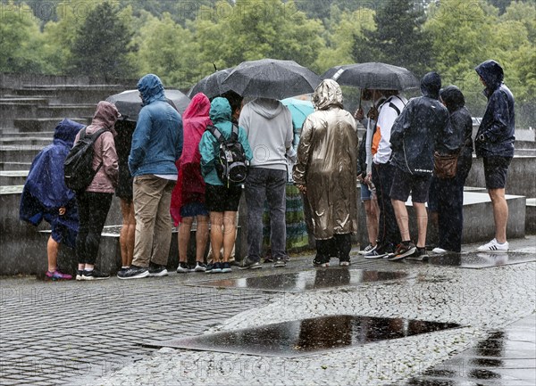 Visitors to the Memorial to the Murdered Jews of Europe protect themselves from heavy rainfall with umbrellas, Berlin, 23 June 2023