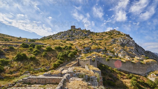 Ancient fortress ruins on a mountain with blue sky and visible path through the grounds, Archaic Castle, Akrokorinthos, Corinth, Peloponnese, Greece, Europe