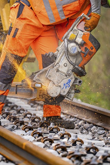 A construction worker uses a chainsaw to cut a track while sparks fly, track construction, Hermann Hessebahn, Calw, Black Forest, Germany, Europe