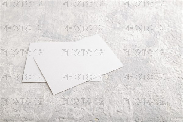 White paper business card, mockup on gray concrete background. Blank, side view, still life, copy space