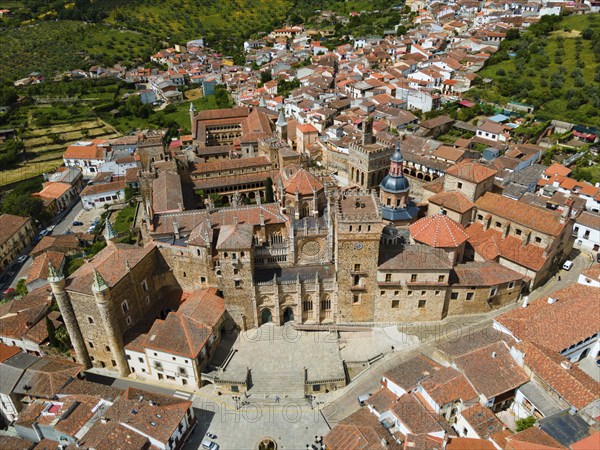 Aerial view of an old monastery with red roofs, surrounded by a village and green hills, presenting the historical architecture in Spain, Aerial view, Sanctuary and Monastery, Real Monasterio de Nuestra Señora de Guadalupe, Guadalupe, Cáceres Province, Caceres, Extremadura, Spain, Europe