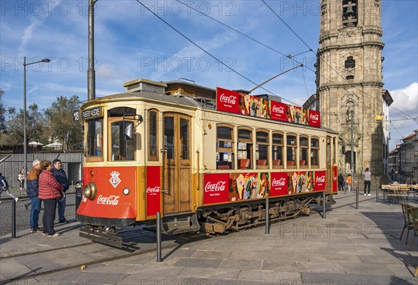 The iconic red tram number 18 pauses in front of the Clérigos Church Tower, Porto, Portugal, Europe