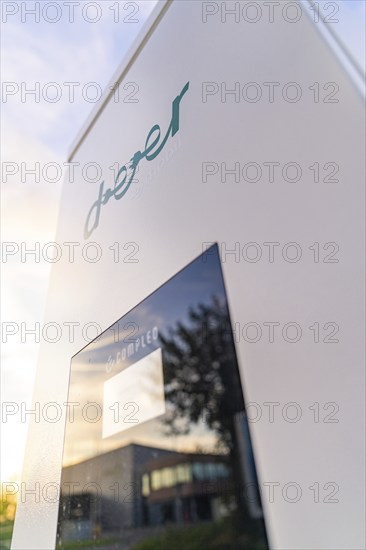 Close-up of a charging station with a reflective screen and a modern building in the background, Calw, Black Forest, Germany, Europe