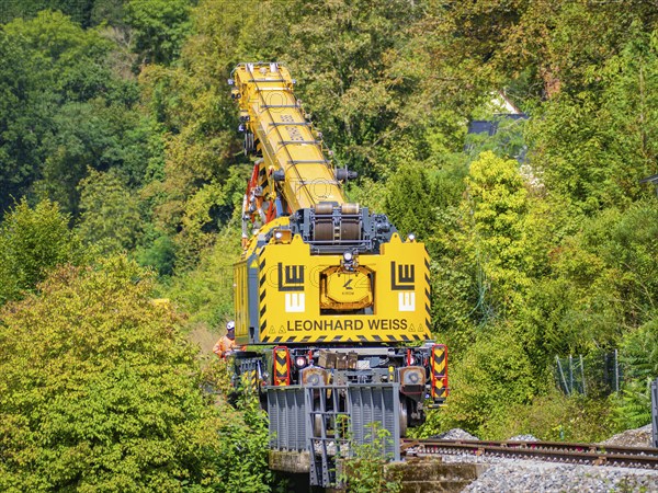 Yellow crane from Leonhard Weiss on a railway line working in a wooded area, track construction, Hermann Hessebahn, Calw, Black Forest, Germany, Europe
