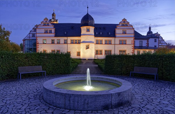 Ehrenstein Castle, a well-preserved Renaissance castle, with castle garden and fountain, illuminated at dusk. Ohrdruf, Thuringia, Germany, Europe