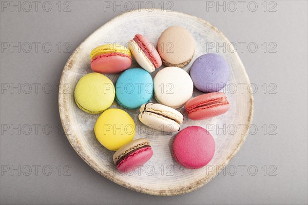 Multicolored macaroons on ceramic plate on gray pastel background. top view, close up, still life, flat lay. Breakfast, morning, concept