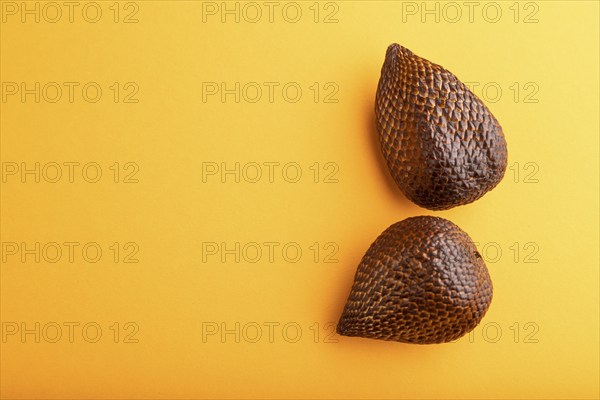 Salak or snake fruit on orange pastel background. Top view, flat lay, copy space. Tropical, healthy food, summer, exotic, minimalism