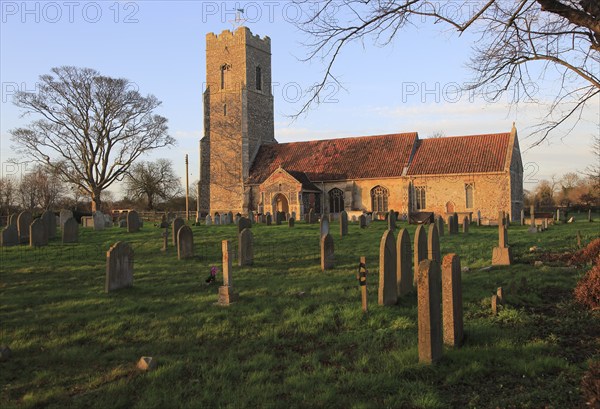 Late afternoon winter golden light falls on Saint John the Baptist church, Snape, Suffolk, England, UK